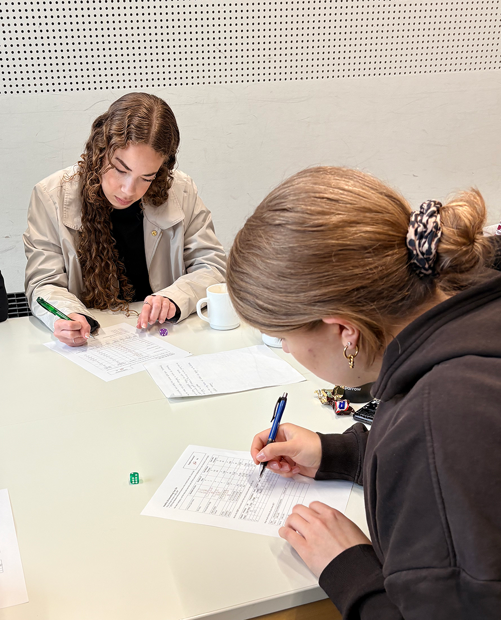 Two students seated at a table, completing an assignment
