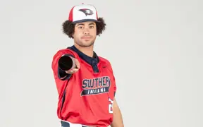 A baseball player points his bat directly at the camera at the baseball media day photo shoot. 