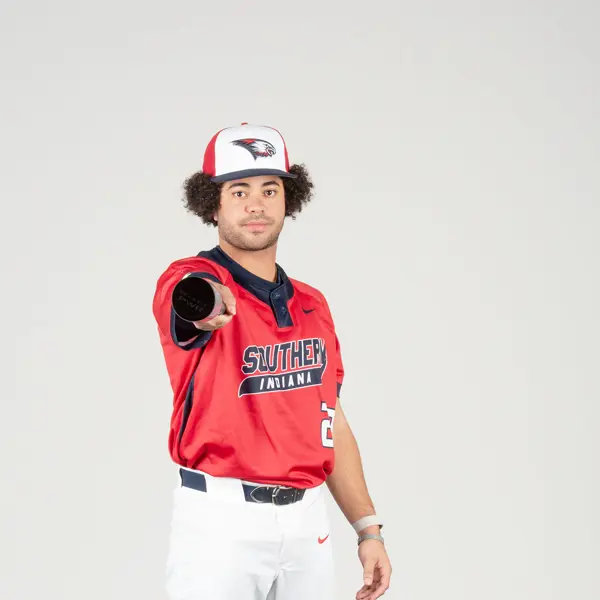 A baseball player points his bat directly at the camera at the baseball media day photo shoot. 