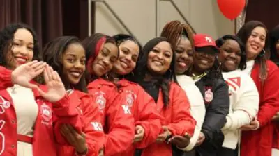 a line of Delta Sigma Theta sorority members posing for a picture wearing their sorority colors.