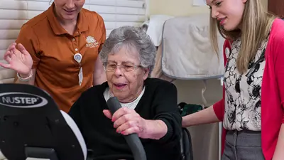 Two USI gerontology students monitor an older adult riding a recumbent stationary bike for exercise