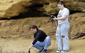 two students taking water measurements along a stream 