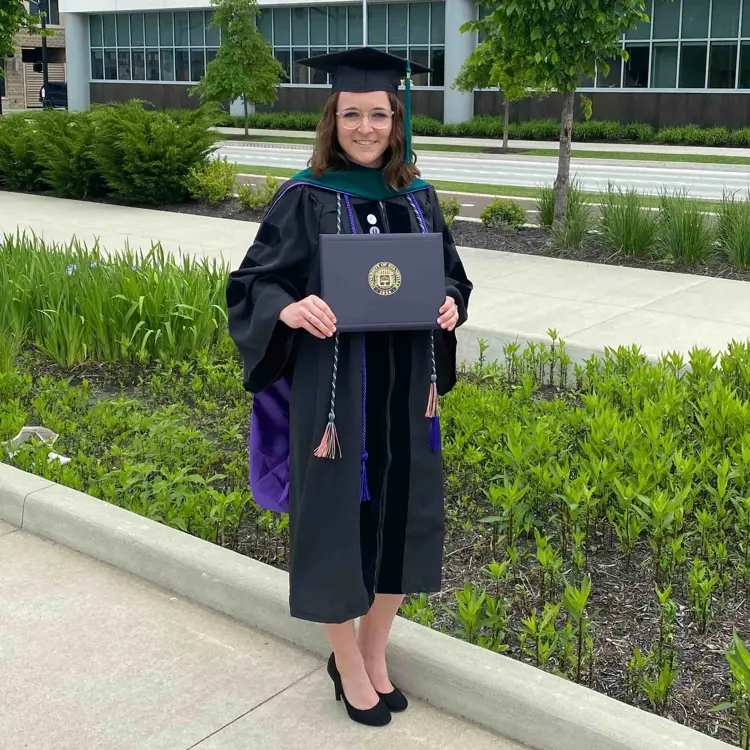 USI graduate physical therapy alumna Jenna Byrley poses with her diploma in her cap and gown