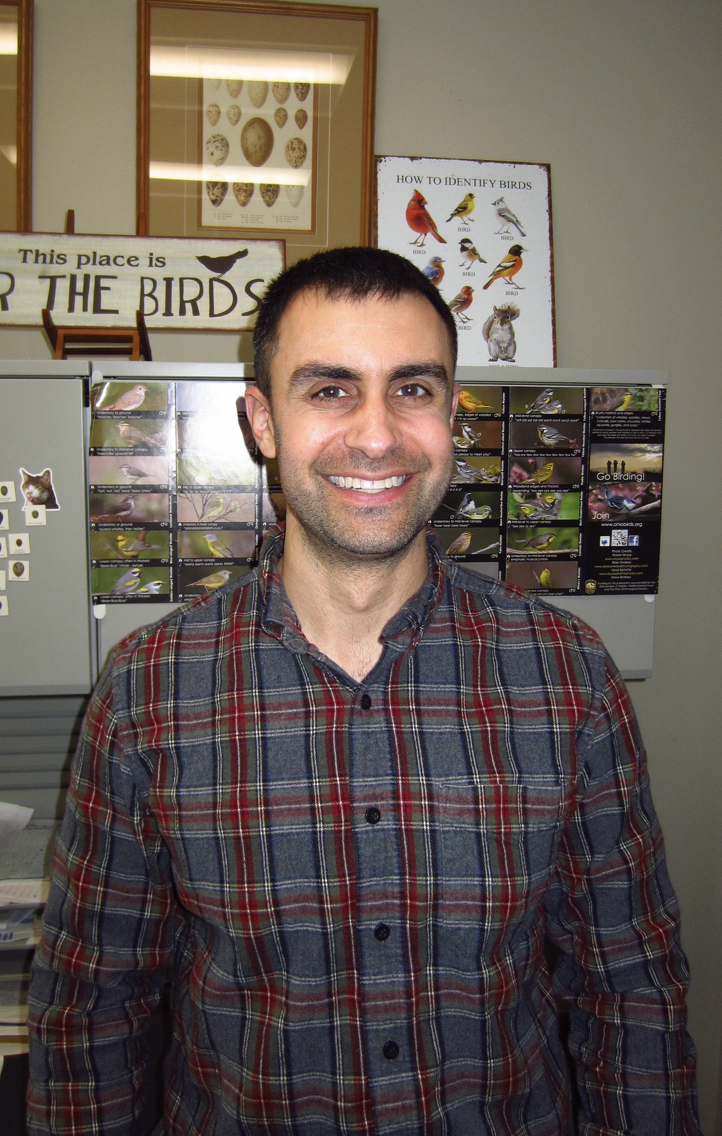 Casual portrait of Dr. Alex Champagne with educational materials about birds in the background