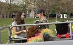 Two students talking and interacting with animals at petting zoo.