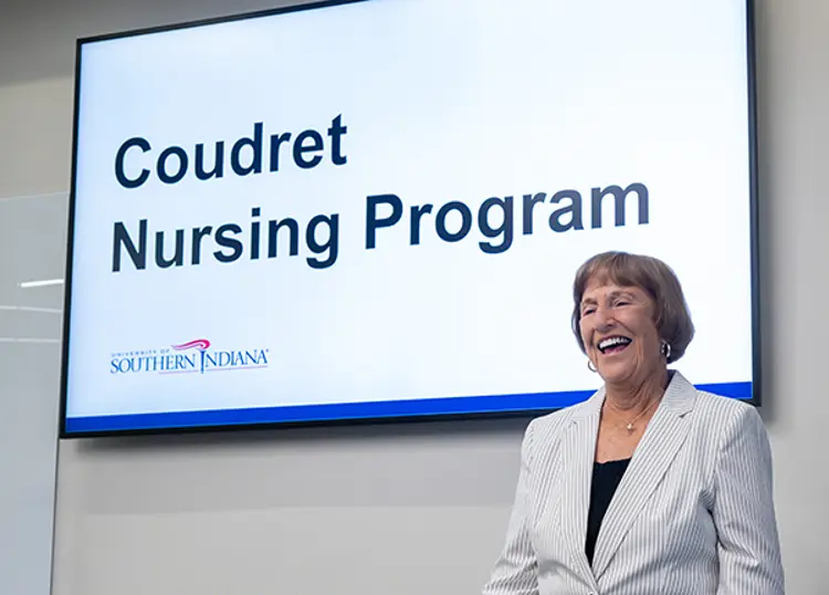Photo of Nadine Coudret in front of sign that says "Coudret Nursing Program"