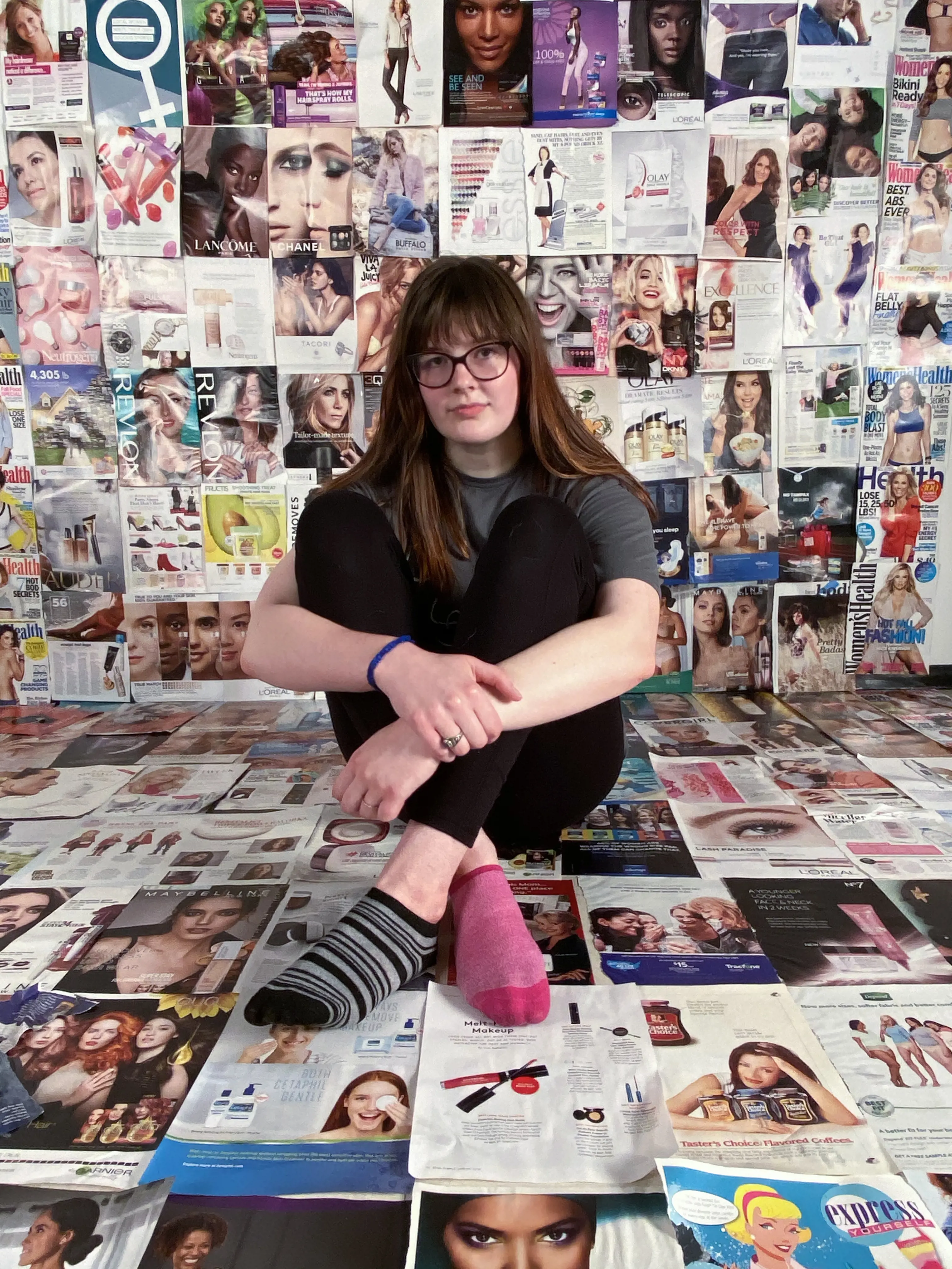 Megan Thorne Photo of woman sitting on the floor in a room covered with fashion images.