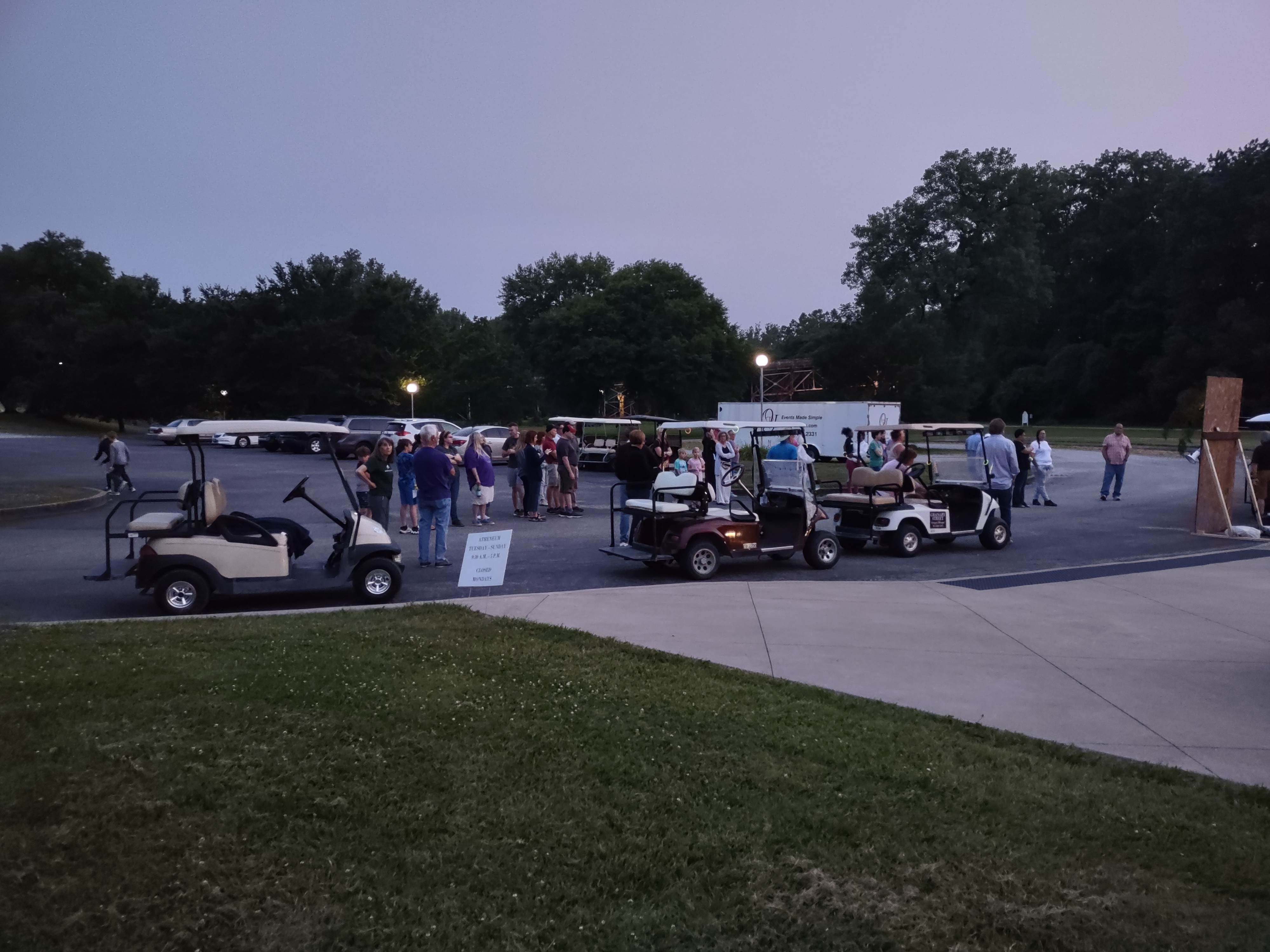 Wide view of the same area with people and golf carts arriving for the event.