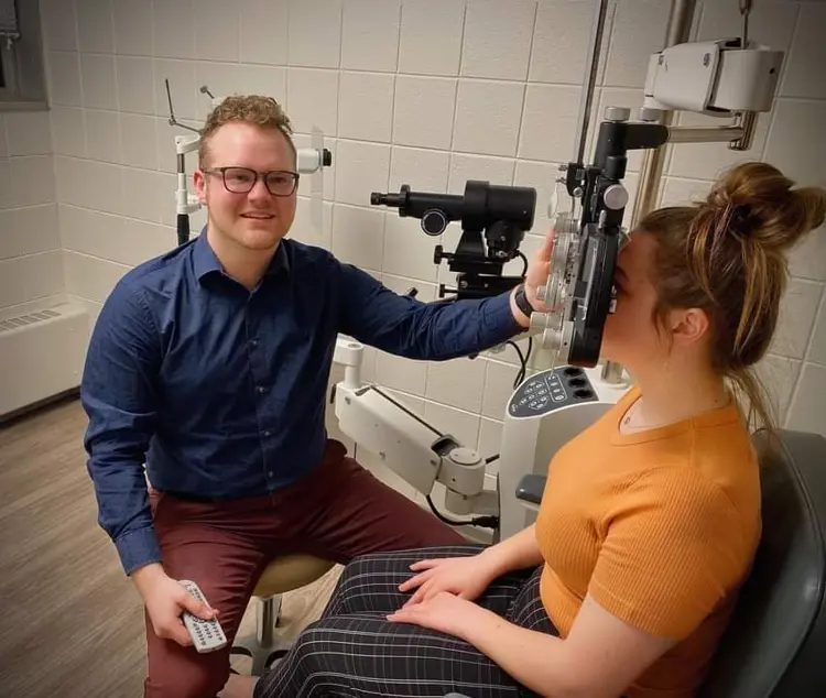 Pre-optometry student Josh Dudek uses a phoropter machine on a practice subject