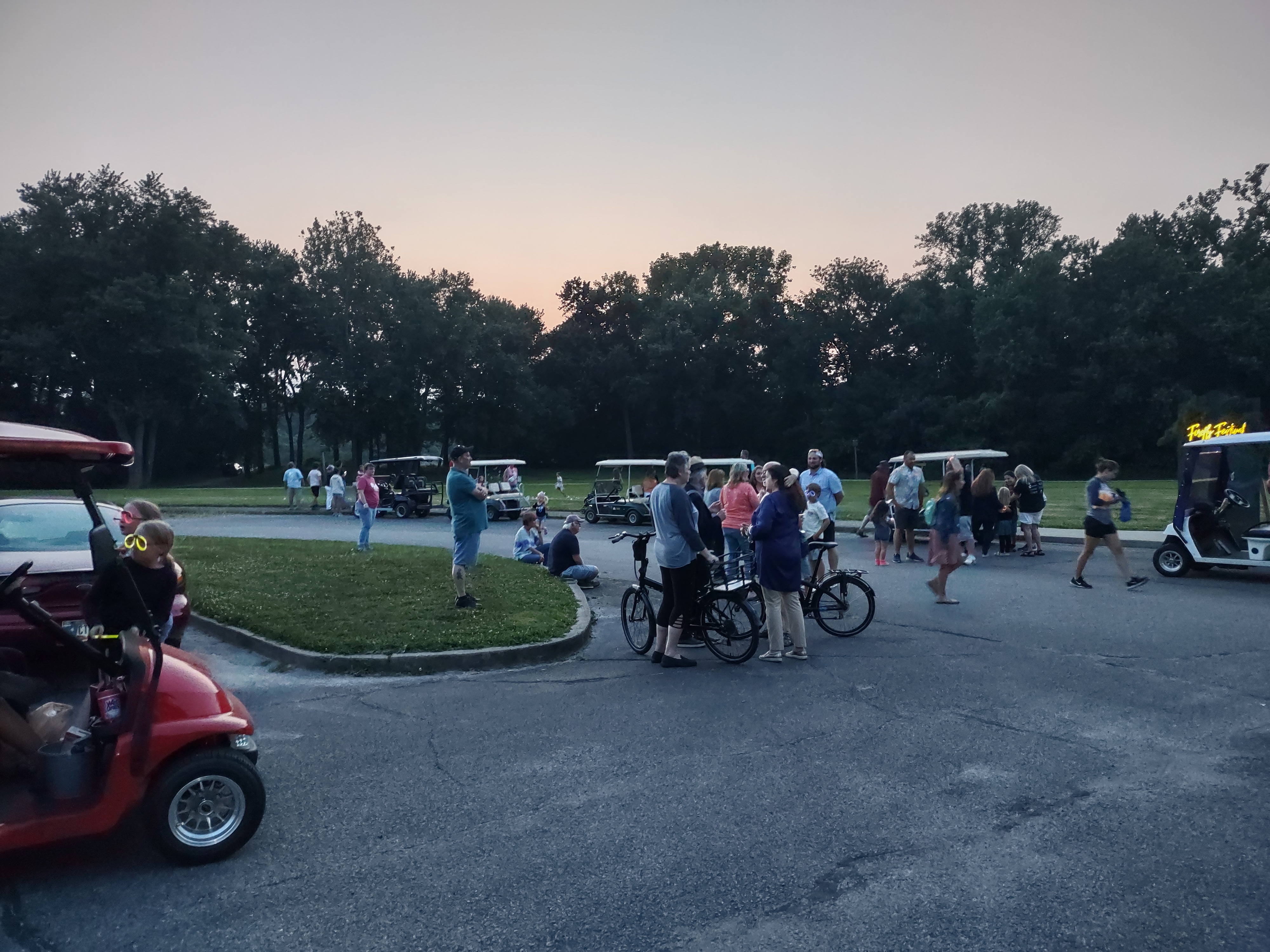 Group gathered in a circular drive area with bicycles and golf carts visible
