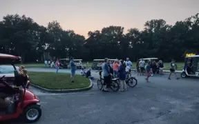 Group gathered in a circular drive area with bicycles and golf carts visible