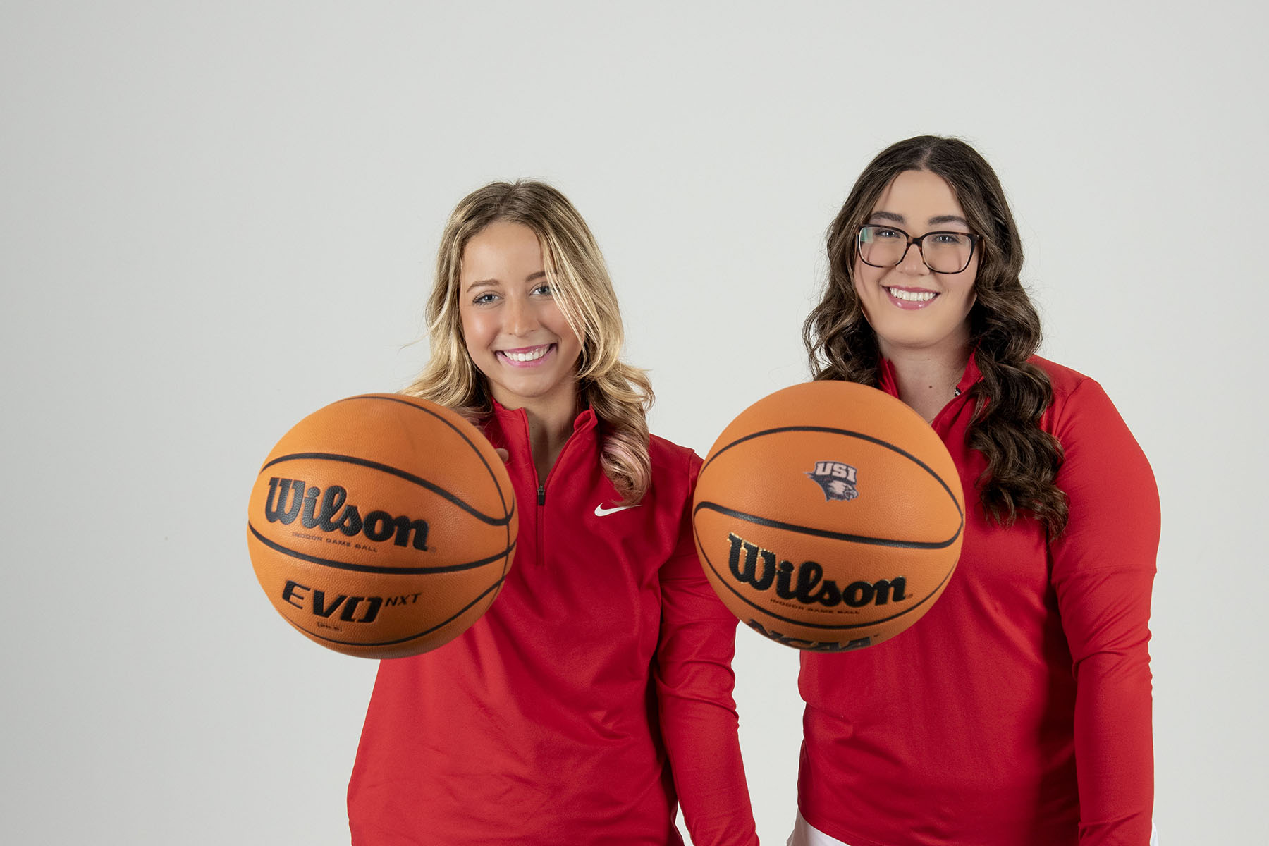 Two members of USI's Women's Golf team palm basketballs admirably during their golf media day photo shoot. 