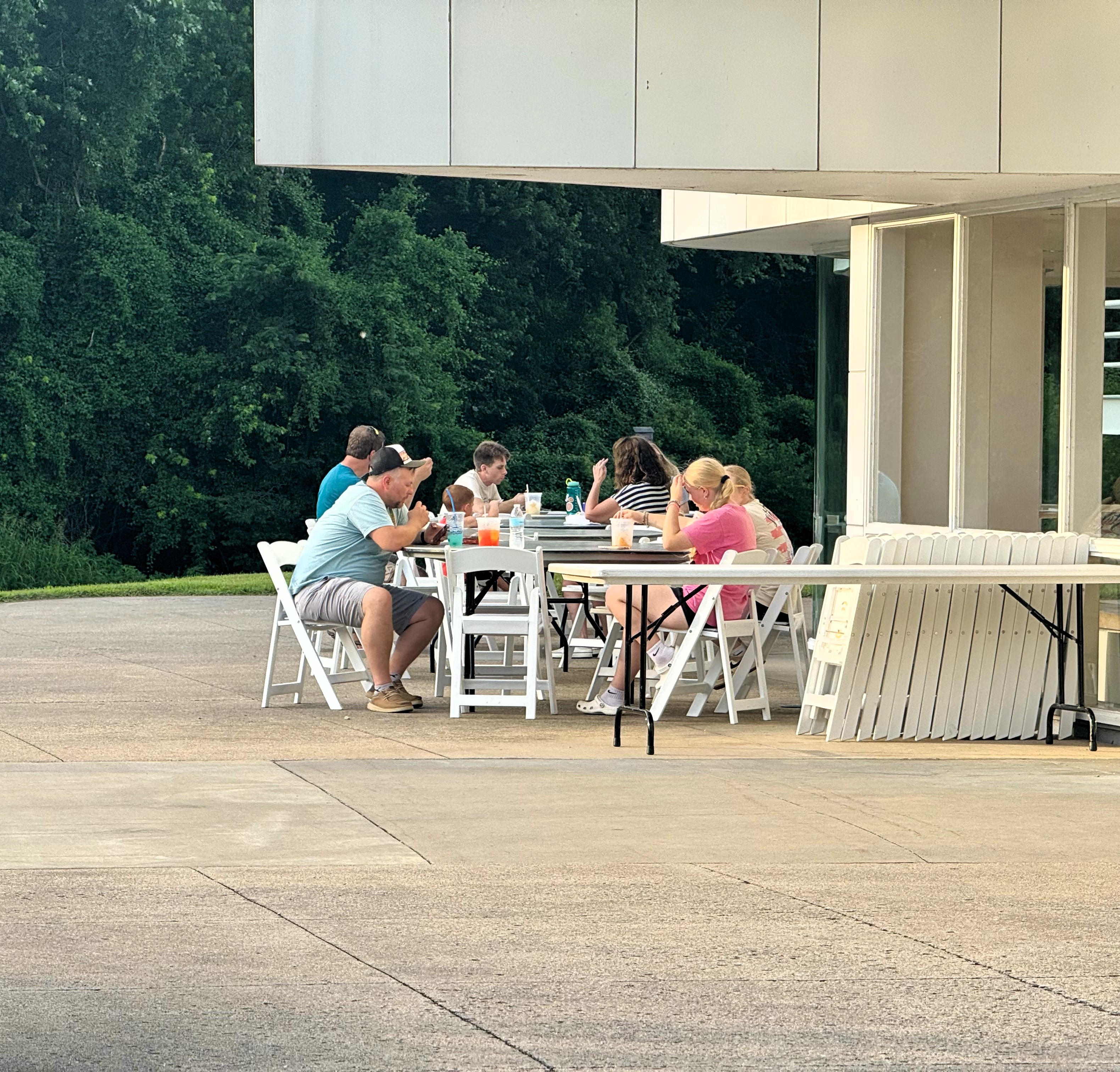 People seated at tables under a pavilion, eating and talking during the event.