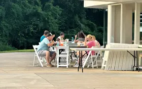 People seated at tables under a pavilion, eating and talking during the event.