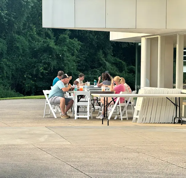People seated at tables under a pavilion, eating and talking during the event.