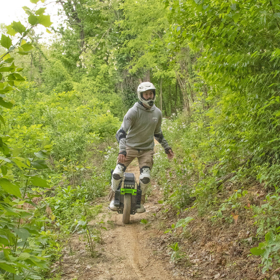 A student on his one-wheel motorized scooter on the mountain bike trails off the Outdoor Education Center at USI.