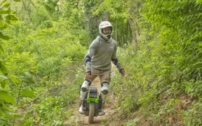 A student on his one-wheel motorized scooter on the mountain bike trails off the Outdoor Education Center at USI.