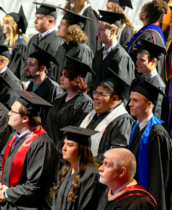 Grads stand in rows awaiting their entrance into the arena.