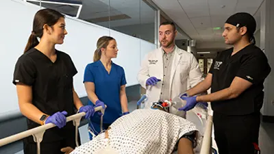 students around a patient bed listening to a faculty member