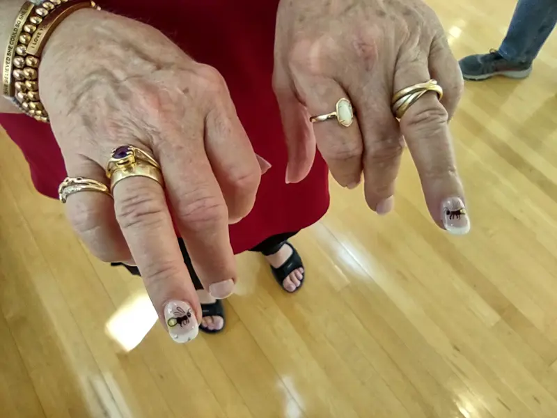 Close-up of hands showing rings and freshly painted fingernails decorated with fireflies.