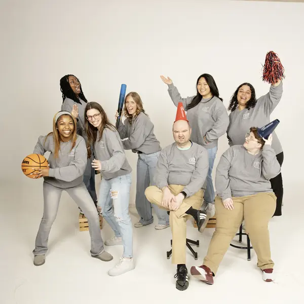 Housing and Residence Life staff  play with athletic props for their informal group photo.